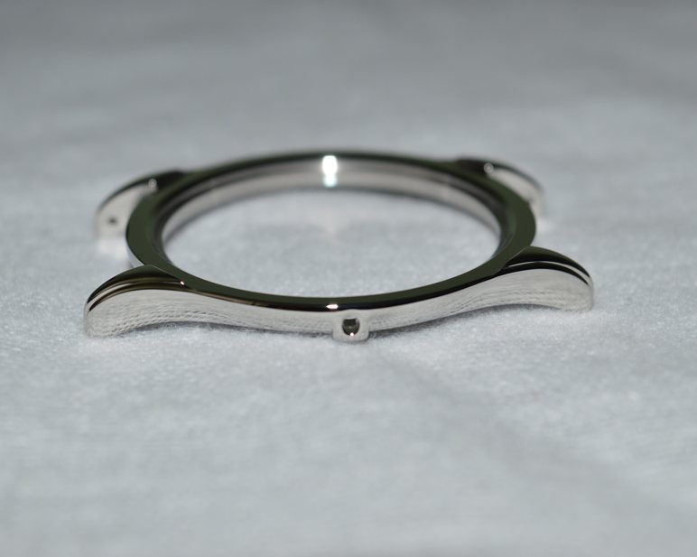 Carrure de montre en acier poli, posée sur un fond gris