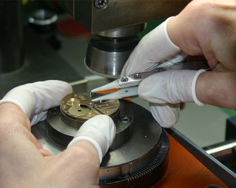 Mains gantées réglant au brucelles un composant sur une machine de décoration