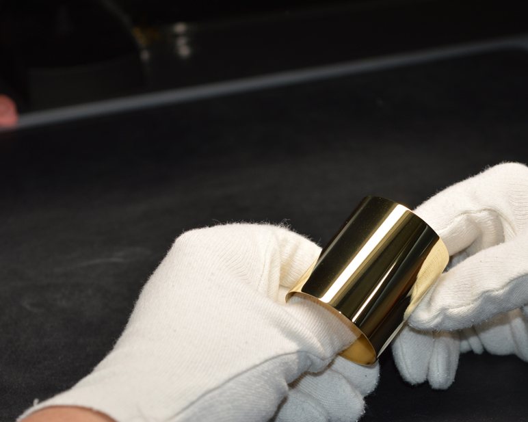 Une pièce dorée tenue entre des mains gantées de blanc