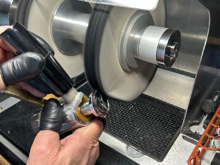 Mains d'un polisseur travaillant une pièce au touret
